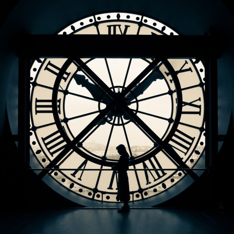 Silhouette of a person standing inside a giant clock face with Roman numerals