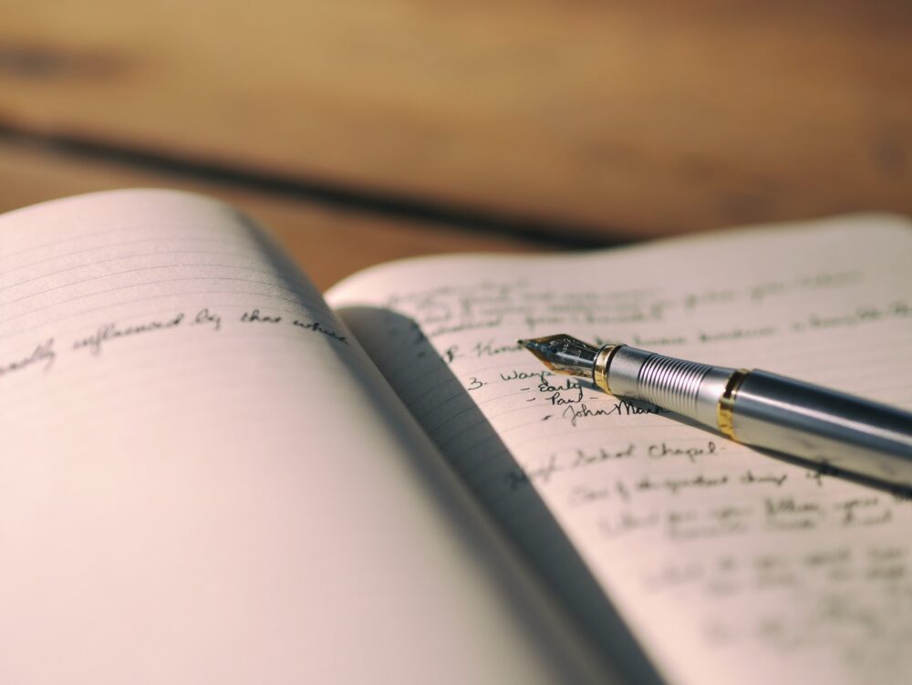 Close-up of a fountain pen resting on an open notebook with handwritten notes