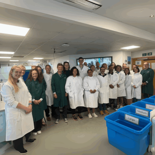 Group of people in lab coats posing together inside a laboratory.