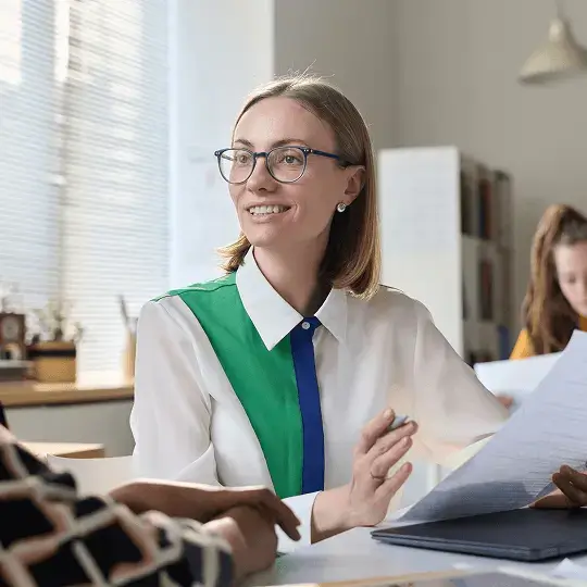 Two women wearing glasses are conversing, showcasing an engaging and friendly interaction between them.
