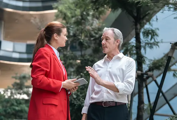 Two people conversing in front of a building, showcasing their interaction against an architectural backdrop.