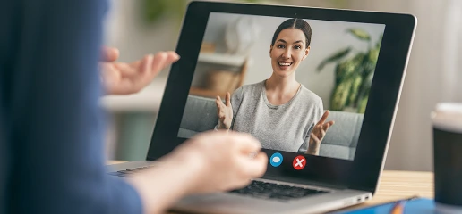 A woman video chatting with friends on her laptop, smiling and engaged in conversation.