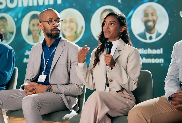 A diverse group of people in chairs, participating in a conversation in a bright, inviting environment.