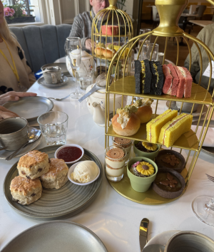 A table displays a birdcage filled with assorted pastries and a teapot, creating an inviting tea party setting.