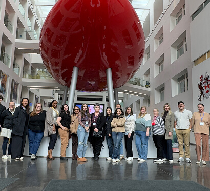 A group of people poses together in front of a large red boat, showcasing camaraderie and maritime adventure.