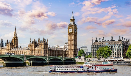 A boat glides by Big Ben and the Palace of Westminster, highlighting the historic architecture of London.