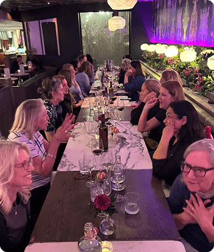 A group of diverse women engaged in conversation while seated around a table.