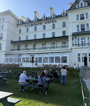 Guests enjoying a meal at picnic tables outside a hotel, surrounded by greenery and a pleasant atmosphere.