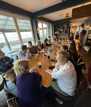 A diverse group of people enjoying a meal together at a restaurant table, engaged in conversation and laughter.