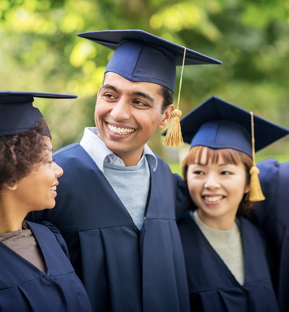 A group of smiling graduates in caps and gowns pose together for a celebratory photo.