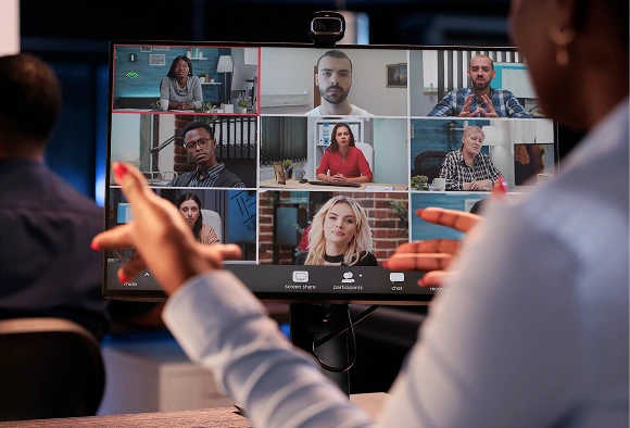 A woman engaged in a video call on her computer, attentively looking at the screen.