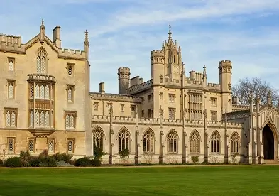 A large building with a well-maintained lawn in front, showcasing a clear blue sky above.