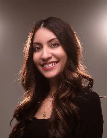 Meli De Los Santos with long hair smiles warmly, exuding a friendly and approachable demeanor.