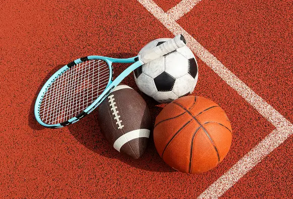 Various sports equipment, including hurdles and cones, arranged on a running track under clear blue skies.