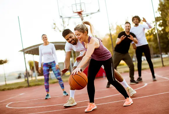 A diverse group of individuals engaged in a basketball game on a court, showcasing teamwork and athleticism.