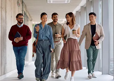 Several people of various ages and ethnicities walking side by side in a corridor.